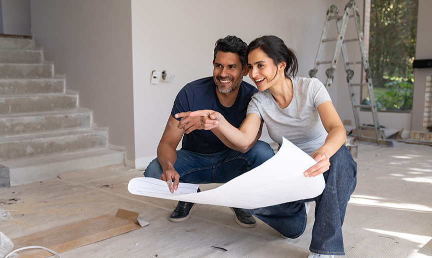 A woman and man holding blueprints of house.