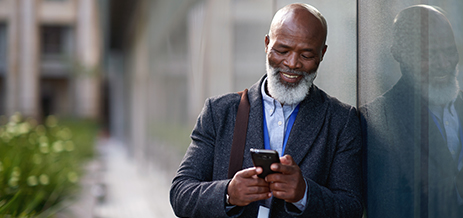 Person leaning against a wall, looking a phone