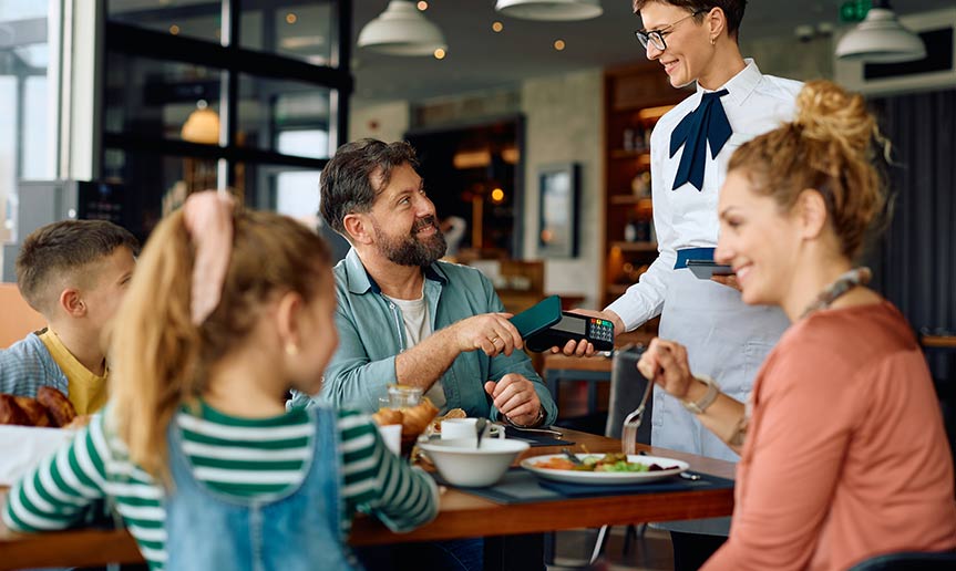 A family at a restaurant paying check with card.